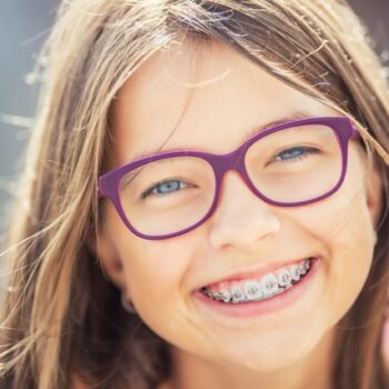 Smiling girl with glasses and braces in sunlight | Orthodontist in Tomball, TX